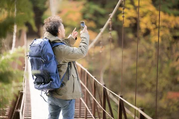Zelfklevend Fotobehang トレッキングや登山して撮影する男性　秋の風景　顔無し © kapinon