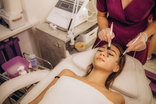 Beautiful woman receiving facial microcurrent procedure for lifting face. Facial rejuvenation and facelift with microcurrent therapy