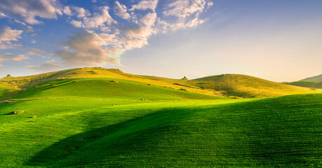 scenery rural view of a contryside farm in green fields and hills with amazing cloudy sky on background