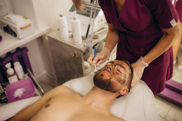 Obraz na płótnie Canvas Cosmetologist applying mask on client's face in spa salon