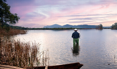 pond landscape in twilight with fisherman fishing on water in vocation day