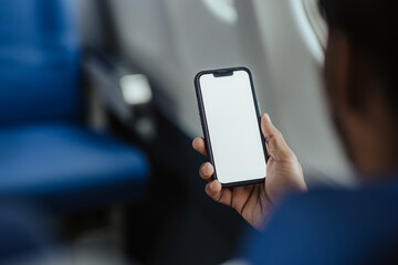 A young man uses a smartphone with a blank screen while boarding an airplane.