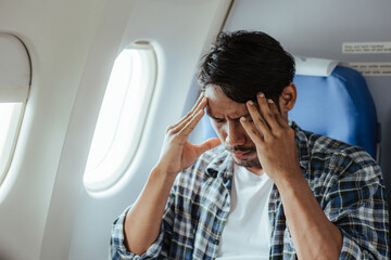 headache on airplane Male passenger is afraid and feels bad while flying on an airplane. - obrazy, fototapety, plakaty