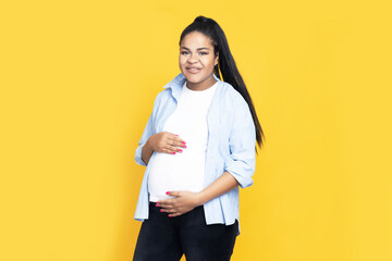 Pregnant African American woman on yellow background.