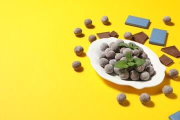 Chocolate balls in a white bowl on a yellow background