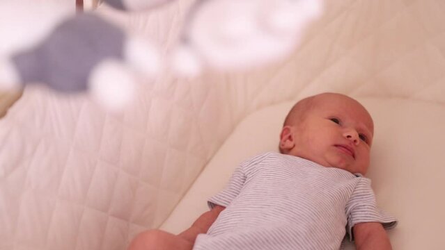 1 month old baby looking around interested in the world in his beige bed