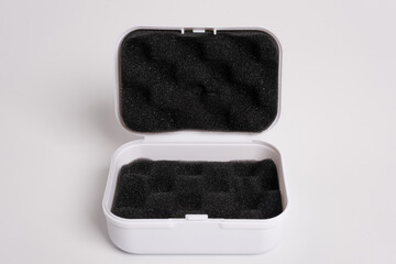 White open box lined with black sponge inside, isolated on a white background. Black mini pouch bag...