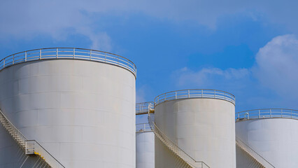 Row of the old white Storage Fuel Tanks in Petroleum Industrial area against blue sky background