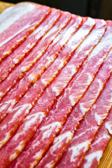 Pork bacon. Fresh pork bacon on a wooden board. Parallel slices of smoked pork belly.