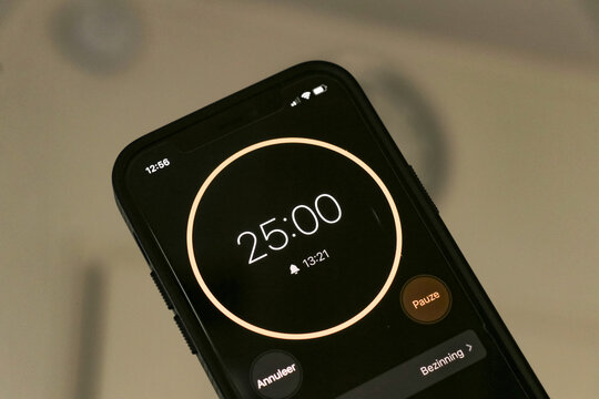 A phone with a black and orange 25-minute timer to study with the pomodoro method on a blurry background