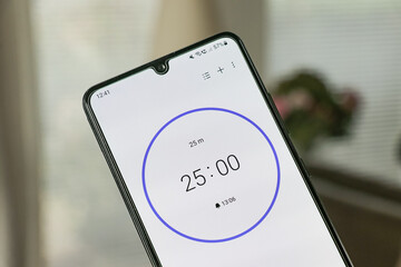 A phone with a white 25-minute timer to study with the pomodoro method on a blurry background