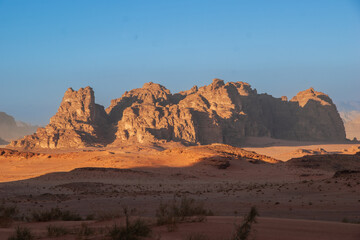 Naklejka premium Jordan. Desert of Wadi Rum. Bizarre shapes of rocks in deserted desert. Landscape is similar to Martian landscapes. Sand is of beautiful pink color in rays of setting sun. Nature concept for design.