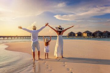A happy family on summer holidays on a beach on the tropical Maldives islands during sunset time,...