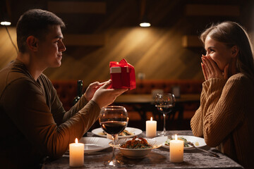 Real candlelight dinner for two, valentine's day date, couple having dinner man giving a woman a...