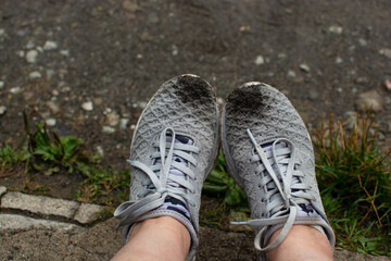 Female legs in sneakers, relaxing outdoors on a rainy summer day, traveling through the mountains
