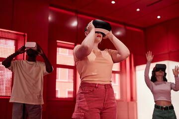 Futuristic waist up portrait of young women wearing VR headsets in red room