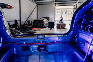 View from the open trunk of a car to the chaotic interior of a car service center. Overall plan.