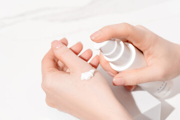 Woman applying hand cream to her hand close-up view. Moisturizing and hand care background.