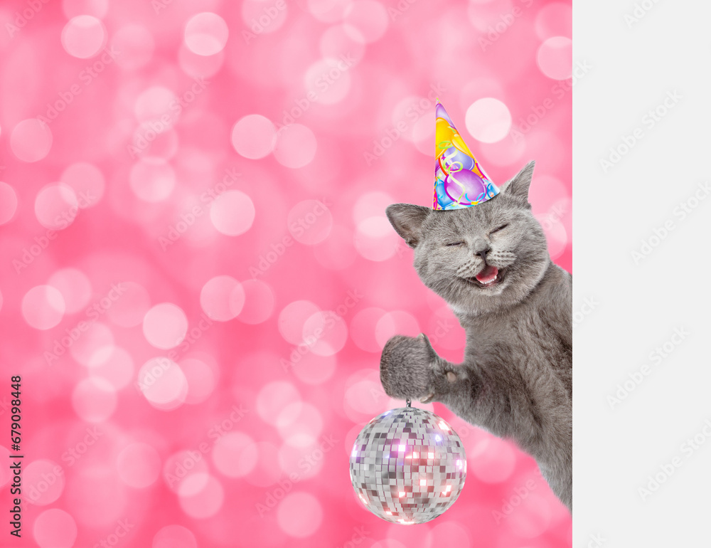Aufkleber Smiling cat wearing party cap looks from behind empty white banner and shows disco ball. Festive background. Empty space for text