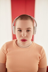 Graphic portrait of gen Z young woman wearing headphones and looking at camera with confidence in futuristic space