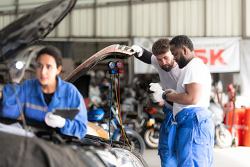 Car mechanic working in an auto repair shop, inspecting the operation of the car's air conditioner and refrigerant, Focus on woman