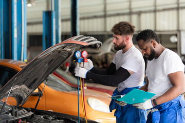 Car mechanic working in an auto repair shop, inspecting the operation of the car's air conditioner...