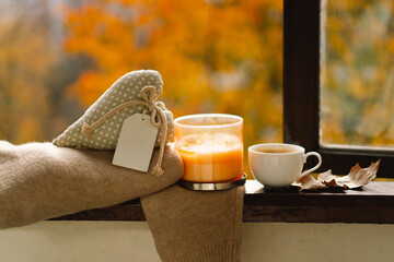 Sweet Home. Still life details in home on a wooden window. Sweater, candle, hot coffee and autumn decor. Autumn home decor. Cozy fall mood. Cozy autumn or winter concept.