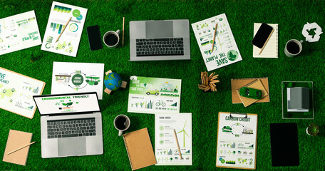 Top view panoramic banner of corporate business plan and research paper for reducing CO2 emission by renewable clean energy technology utilization on meeting table as hub of eco workspace. Quaint