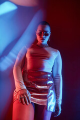 Fototapeta na wymiar Fashion portrait of confident curvy woman wearing short skirt posing in neon light with distortion