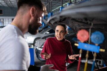 Car mechanic working in an auto repair shop explain to customer after inspecting the operation of the car's air conditioner and refrigerant - obrazy, fototapety, plakaty