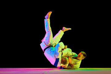 Athletic men, professional sportsmen during match. Judo fighter attacking his opponent with leg...
