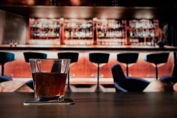 Glass of whiskey on the bar in front of the blur image bar