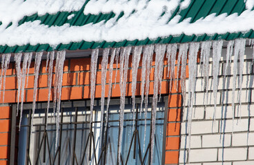 Icicles hang from the roof of the house. Winter