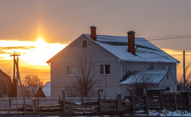 Country house in the snow at sunset