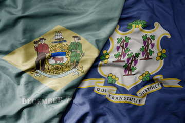 big waving colorful national flag of connecticut state and flag of delaware state .