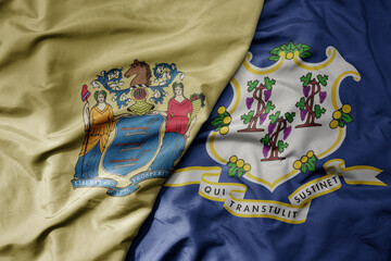 big waving colorful national flag of connecticut state and flag of new jersey state .