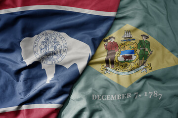 big waving colorful national flag of delaware state and flag of wyoming state .