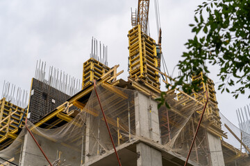 Steel reinforcement structure of rebars for concrete pouring and protective mesh against falling on construction site.  monolithic concrete frame of apartment block building under construction