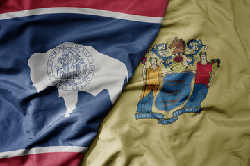big waving colorful national flag of wyoming state and flag of new jersey state .