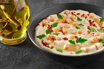 Hummus with oil, chickpeas and spices in bowl, selective focus
