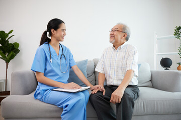 caregiver or nursing home holding hands and talking with senior man on sofa