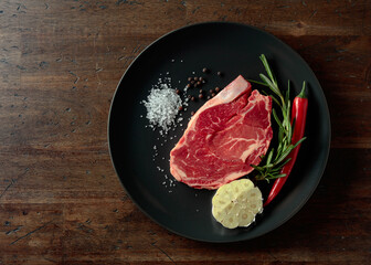 Raw beef steak with rosemary, garlic, salt, and pepper.
