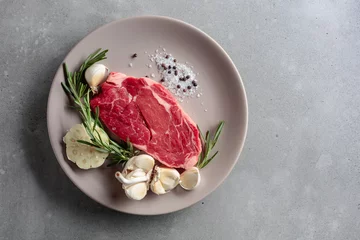 Rolgordijnen Raw beef steak with rosemary, garlic, salt, and pepper. © Igor Normann