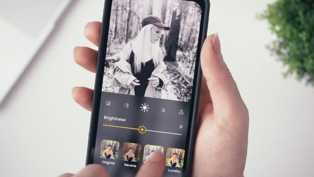 Woman editing her photo for social media. Stylizing images using an online app, choosing between different photo filters. Fictional interface.
