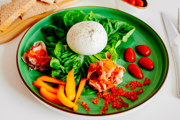 Burrata cheese served with tomatoes, yellow peppers, and red fish. Italian appetizer. The concept of a vegetarian lifestyle and healthy eating.