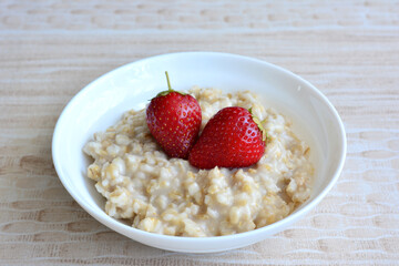 porridge in white bowl with fresh strawberry