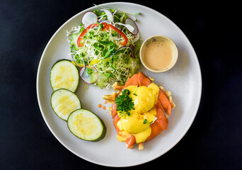 white plate with eggs bennedict waffles with smoked salmon on a white background