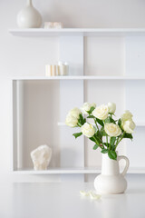 white roses in white jug in white interior