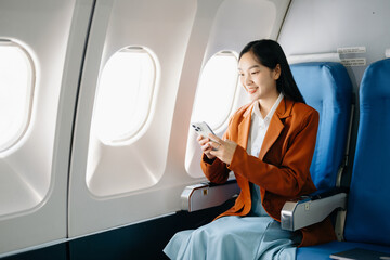 Asian executive excels in first class, multitasking with digital tablet, laptop. Travel in style,...