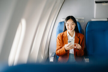 Asian executive excels in first class, multitasking with digital tablet, laptop. Travel in style,...